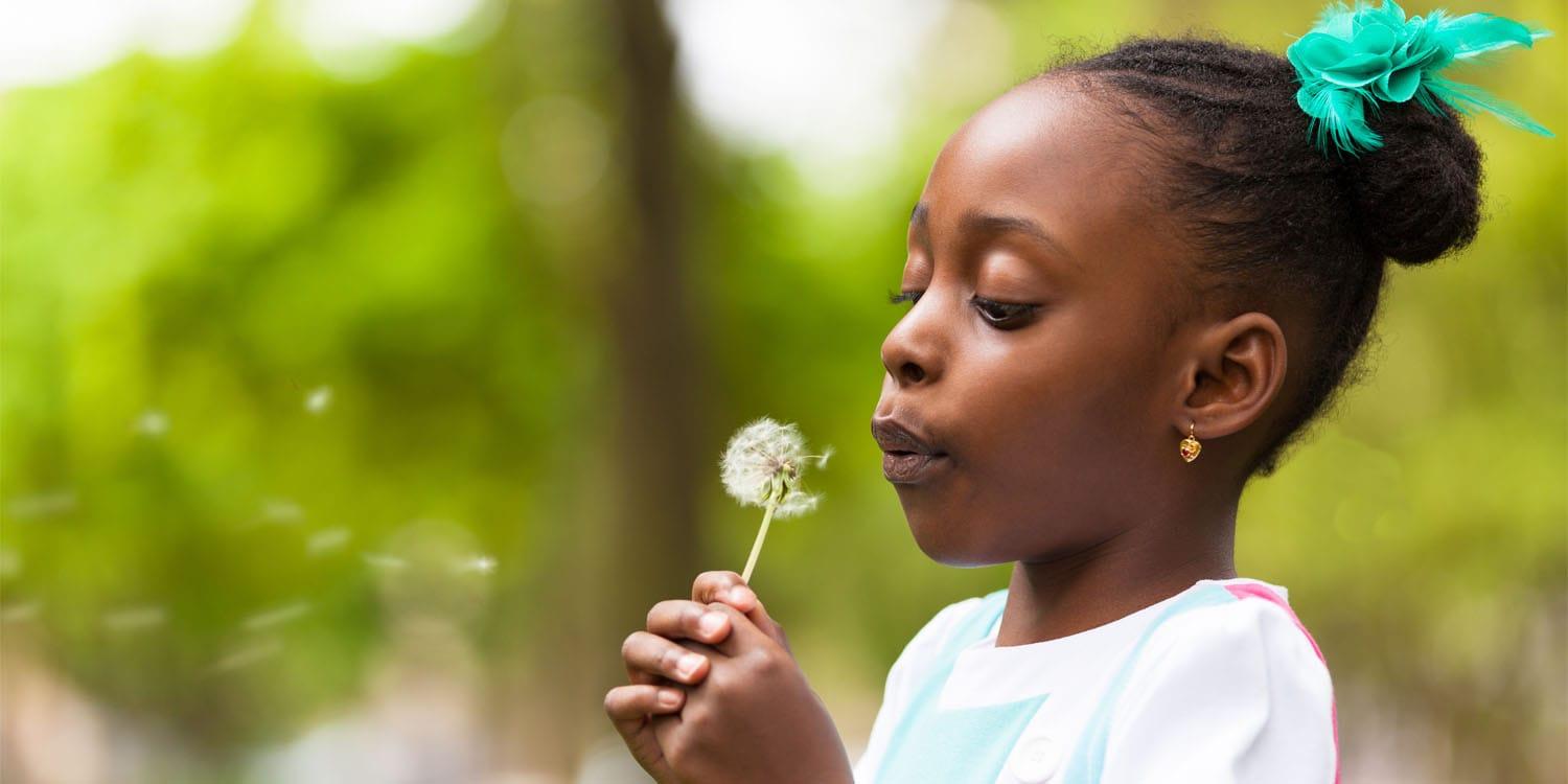 Outdoor-portrait-of-a-cute-young-black-girl-blowing-a-dandelion.jpg